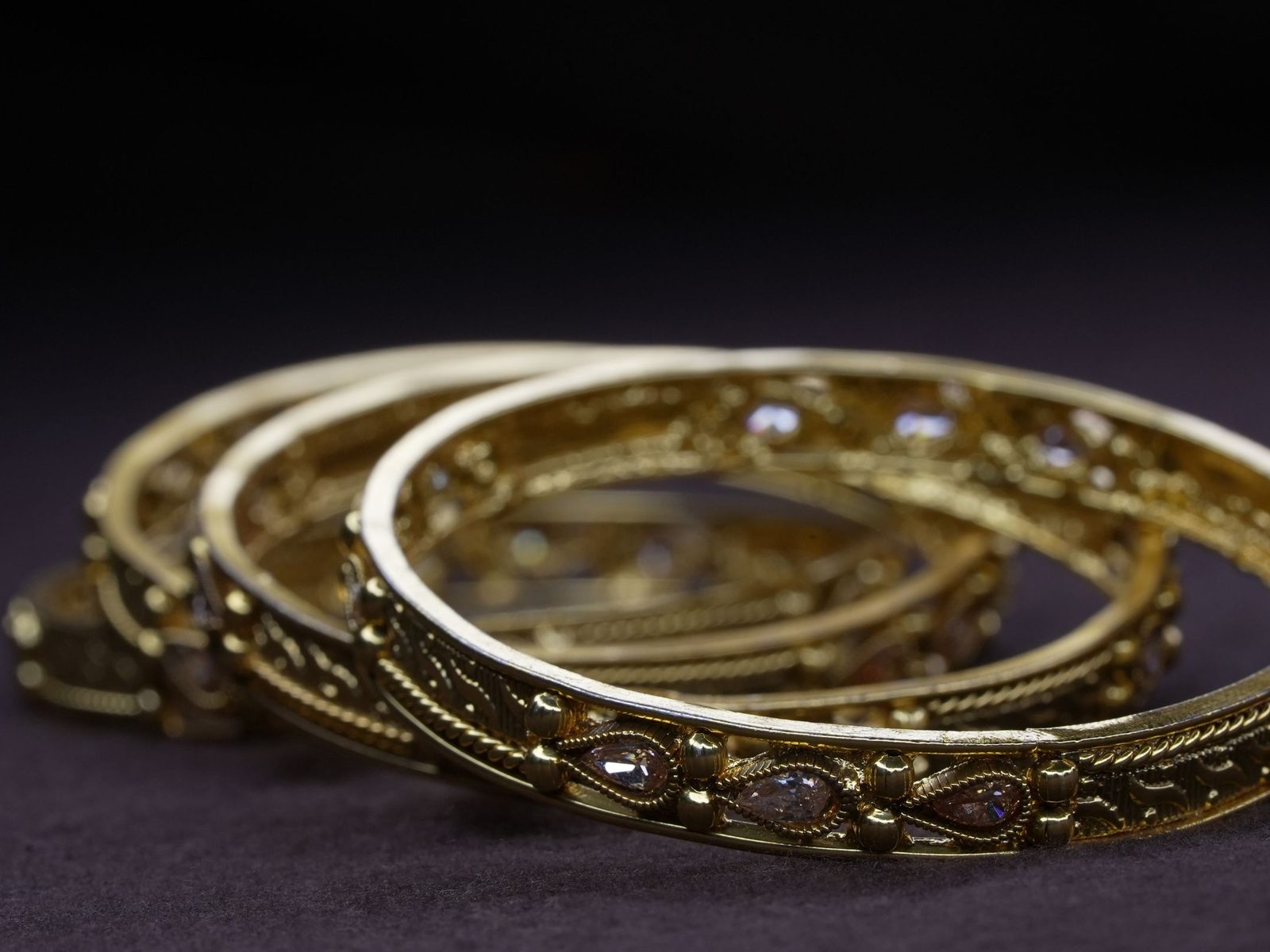 Intricate gold bangles on a dark background